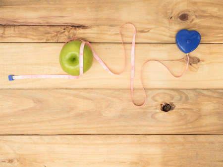 blue dumbbell and measure and green apple on wooden background with copy spaceの写真素材