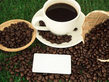 Cup of coffee and coffee beans on wooden spoon and and biscuit on grass green backgroundの写真素材