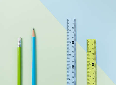 Green pencil, ruler and blue pencil, ruler on green and light blue background.