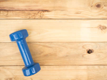 blue dumbbell isolated on wooden background with copy spaceの写真素材