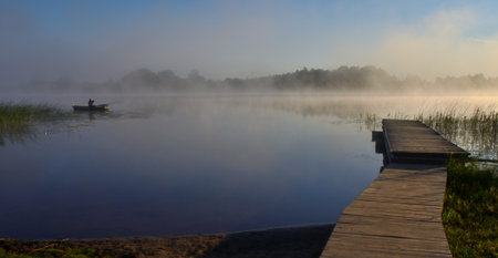 Foggy morning on the lake with wooden pier in the foregroundの写真素材