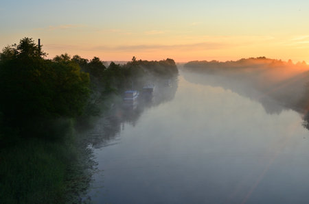 Sunset on the river in the summer with fog and trees.の写真素材
