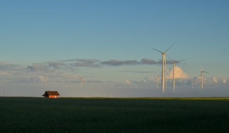 Wind turbines in a field with a farm house in the background.