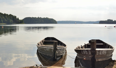 Two old wooden boats on the shore of a lake in the summerの写真素材