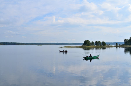 Fishermen in a boat are fishing on the shore of the lakeの写真素材