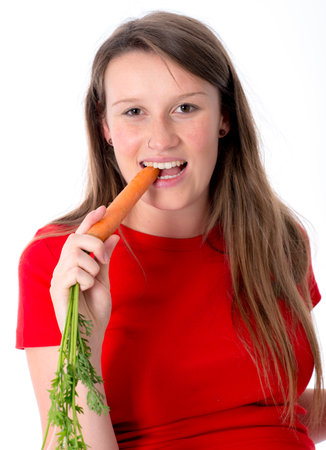 young pregnant woman in red shirt is eating carrotの写真素材