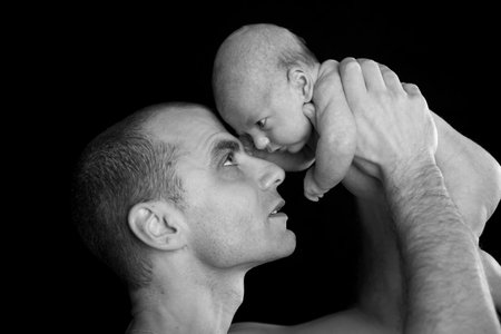 father and baby in front of black background