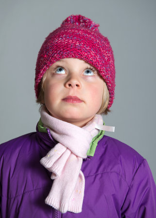 girl with with scarf and woolen hat in front of gray background