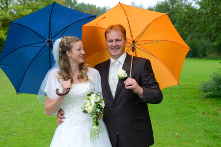 blond bridal couple in front of nature background with umbrellaの写真素材