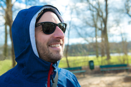 young man in front of nature background with hoodie sweater is smiling