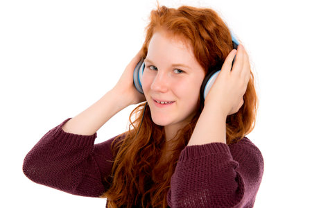 red haired girl is listening music with blue headphoneの写真素材