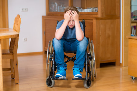 disabled boy in wheelchair at home is sad
