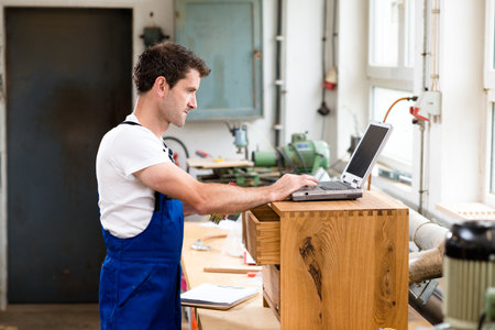 worker in a carpenter's workshop using computerの写真素材