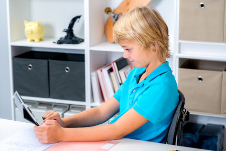 blond boy using tablet computer in his roomの写真素材