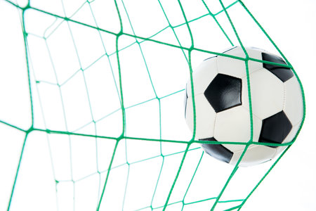 soccer ball in green goal in front of white backgroundの写真素材