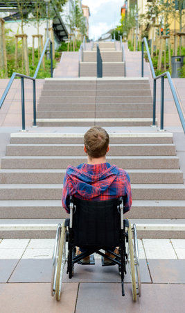 young disabled man in wheelchair in front of stairsの写真素材