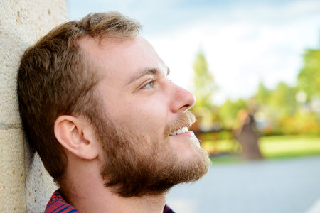 young bearded man lean on wall and looking relaxed