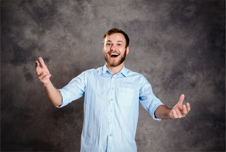 young bearded man is surprised and showing open handsの写真素材