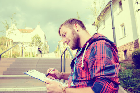 young man with beard standing with book and readingの写真素材