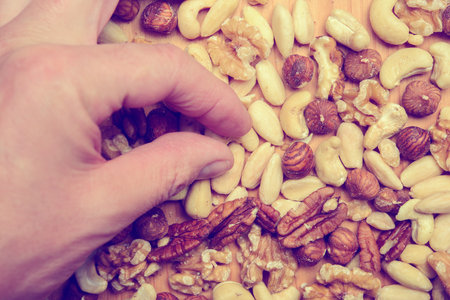 hand with different nuts on wooden ground from aboveの写真素材