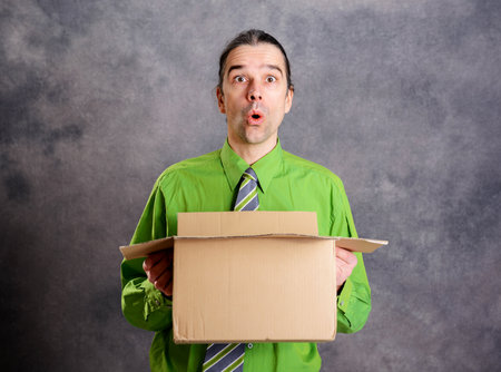 young man opening a package and looking surprisedの写真素材