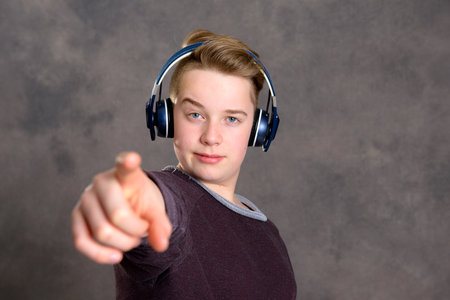 teenager with headphone listening music and pointing in to the camera