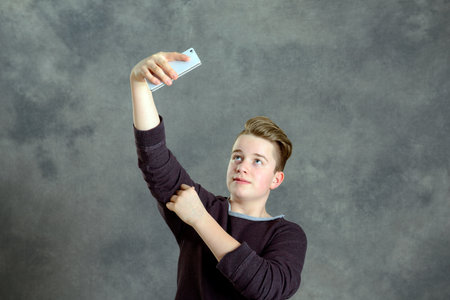  teenager in brown sweatshirt take a self-portrait with phone の写真素材