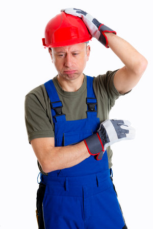 young workman in blue dungarees and red hard top thinkingの写真素材