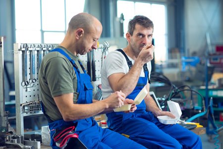 two worker in factory have a break on work bench