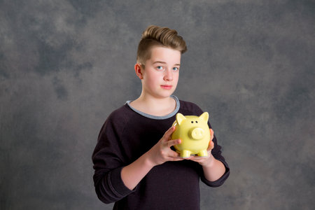 teenager in brown sweatshirt showing piggybankの写真素材