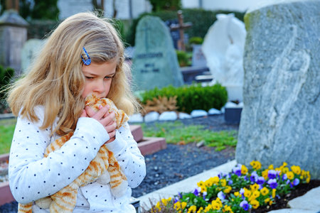 little sad girl in front of graveの写真素材