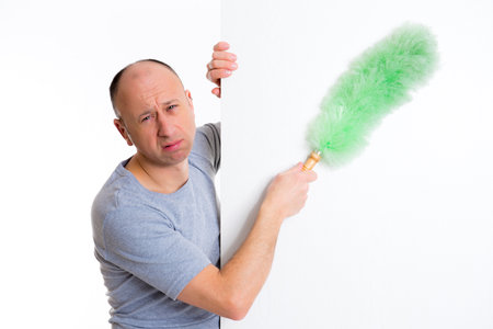 young man cleaning with feather duster in front of white background