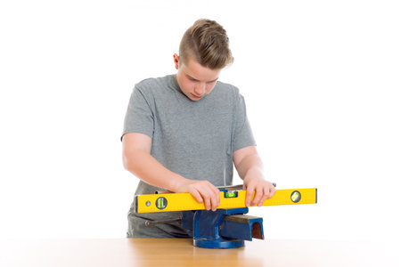 teenager in professional training with spirit level in front of white backgroundの写真素材