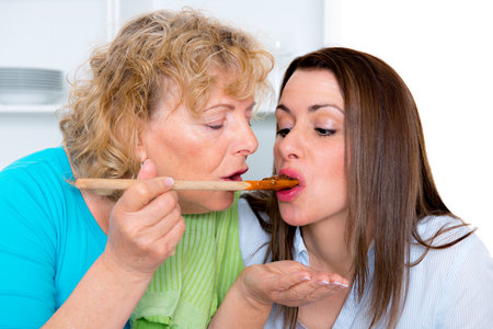 young woman and her mother cooking together in the kitchenの写真素材