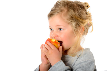 sweet girl eating apple in front of white backgroundの写真素材