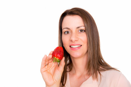 Nice young woman eating strawberry looking surprisedの写真素材