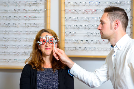Young optician checking eyes of woman for new glassesの写真素材