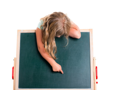 blond girl showing with forefinger to blackboard in front of white backgroundの写真素材