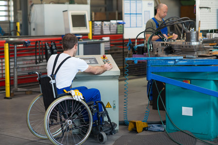 disabled worker in wheelchair in factory on the machineの写真素材