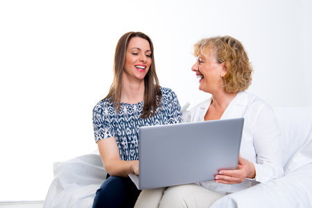 young woman and her mother with laptop in front of white backgroundの写真素材
