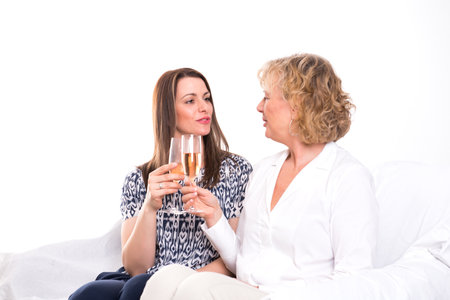 young woman and her mother drinking champagne  in front of white backgroundの写真素材