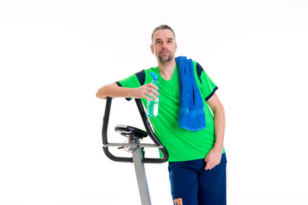 young man in green shirt with water bottle train with fitness machineの写真素材