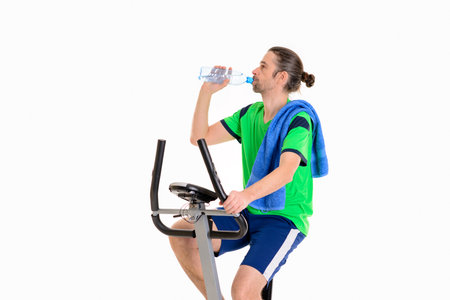young man in green shirt with water bottle train with fitness machineの写真素材