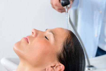 hairdresser washing womans hair in his shopの写真素材