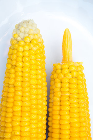 two corncobs on plate on wooden groundの写真素材