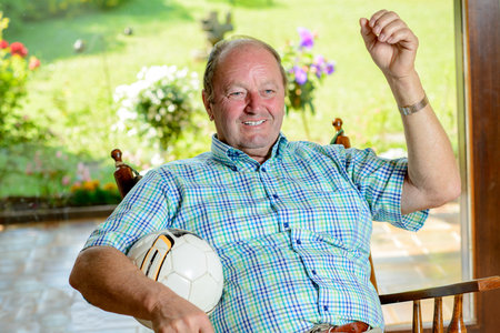 senior in rocker chair watching football match in the tvの写真素材