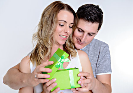 Young beautiful couple with gift box in front of white backgroundの写真素材