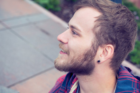 Young bearded man in checkered shirt in front of urban background