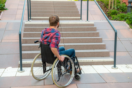 young disabled man in wheelchair in front of stairsの写真素材