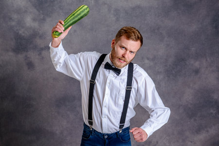 young angry vegetarian minatory with zucchini cudgelの写真素材